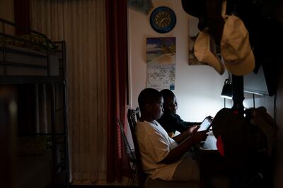 Adam Schneider, 7, centre right, reads on a tablet computer with his older brother Isaiah, 9, in their bedroom, on December 8, 2021, in Brooklyn, New York. Their mother April Schneider says she is lucky her two oldest children attend the same school and can share technology. AP