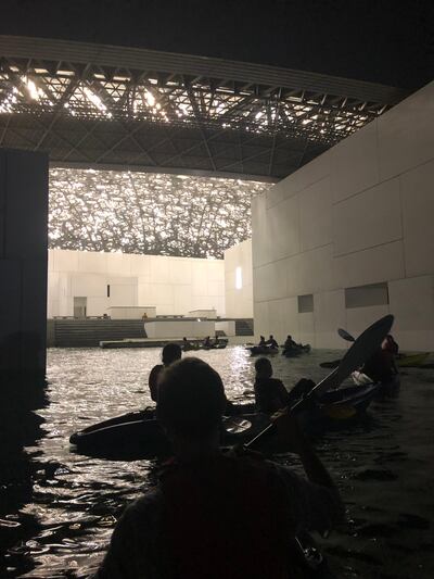 Guests kayak around Louvre Abu Dhabi in the evening. 