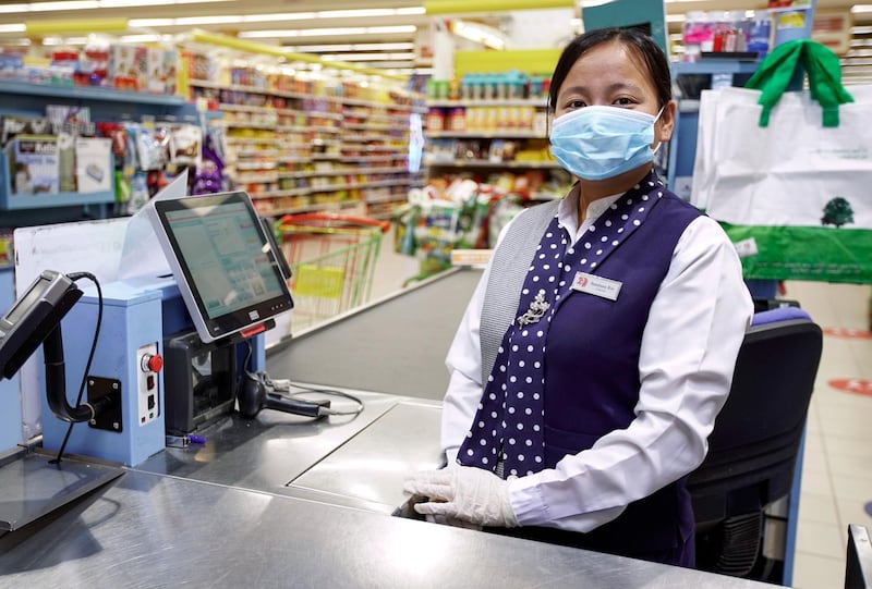 Bandana Rai, from Nepal, is a cashier at Lulu Hypermarket, Khalidiyah Mall in Abu Dhabi. It is among the few stores allowed open to ensure shoppers can get essentials. She says she feels safe because the company has installed thermal scanners and has given staff gloves and masks. Victor Besa / The National