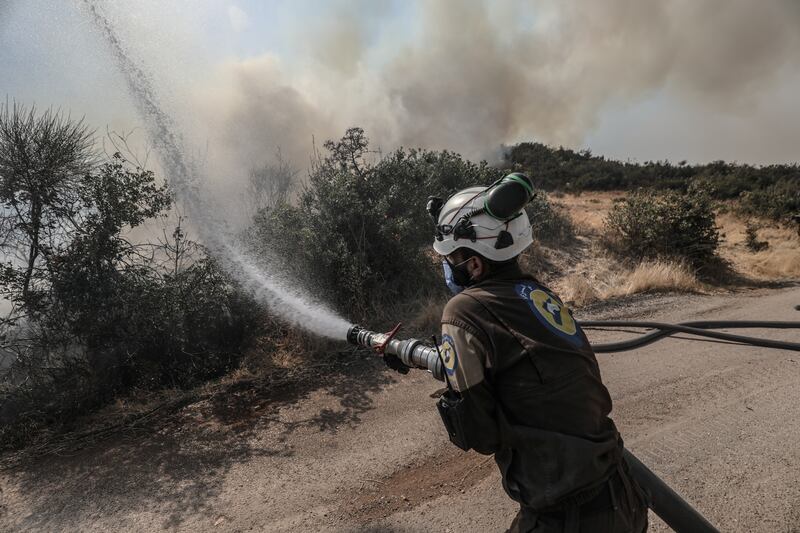 A 'White Helmet' Syria Civil Defence worker tries to  extinguish the flames, during a bad year for fires in Syria. Getty