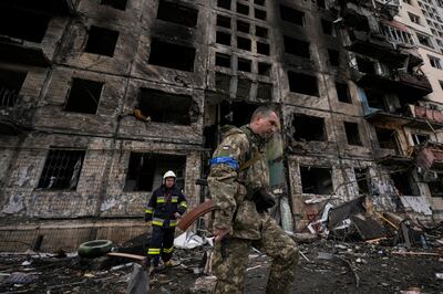 A Ukrainian soldier and firefighter search around a destroyed building after a bombing attack in Kyiv. AP Photo