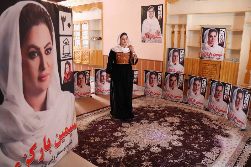 Seemi Barakzai, a candidate for upcoming Wolesi Jirga (Lower House of the Parliament) elections stands next to posters of her during an election campaign in Herat, Afghanistan. EPA