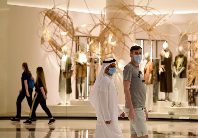 People wearing masks for protection against the coronavirus, walk in the Mall of Dubai on April 28, 2020, after the shopping centre was reopened as part of moves in the Gulf emirate to ease lockdown restrictions imposed last month to prevent the spread of the COVID-19 illness.  / AFP / Karim SAHIB
