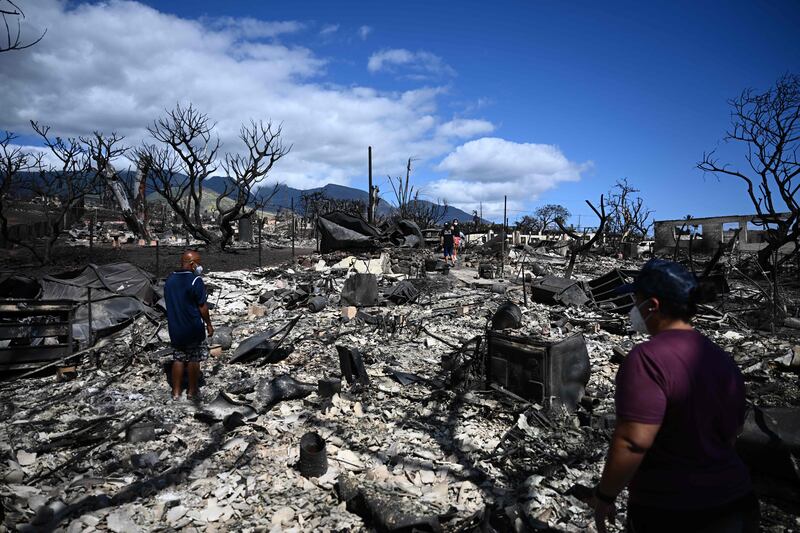 The Ganer family survey the ruins of their home on Malolo Place, western Maui, Hawaii, after a wildfire that killed 67 people.  AFP