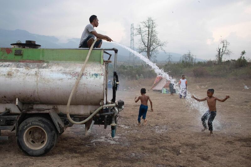 Residents playing with water on a field next to their temporary shelter in the village of Sugian on Indonesia's Lombok island, after a series of recent earthquakes. AFP