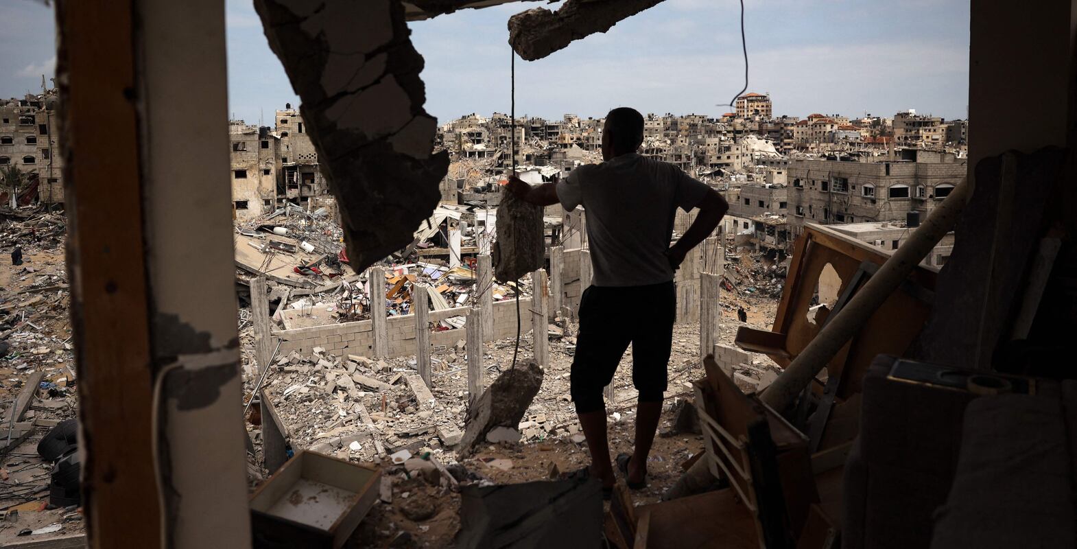 TOPSHOT - A Palestinian man looks at a ravaged neighbourhood from a destroyed apartment in Khan Yunis in the southern Gaza Strip on May 2, 2024, amid the ongoing conflict between Israel and the Hamas movement.  (Photo by AFP)