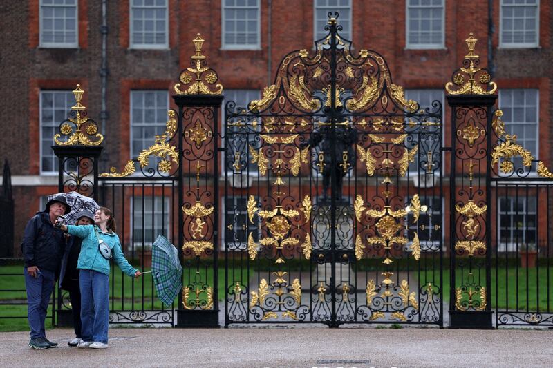 People pose outside the gates of Kensington Palace in London. AFP