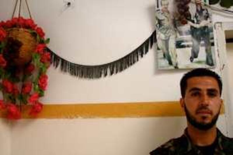 JULY 2009, GAZA: Ismail, wearing his uniform at home in front of a photo of Yassir Arafat. Erin Cunningham for The National *** Local Caption ***  Bros4.jpg