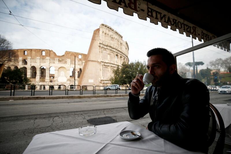 A man sips coffee in front of the Colosseum after its reopening in Rome. AP Photo
