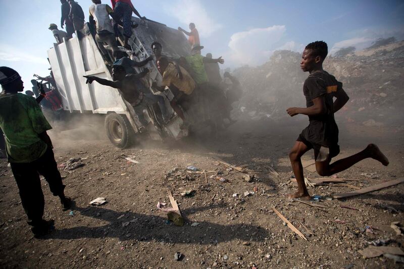 Scavengers climb on a trash truck arriving to unload at the Truitier landfill. AP Photo