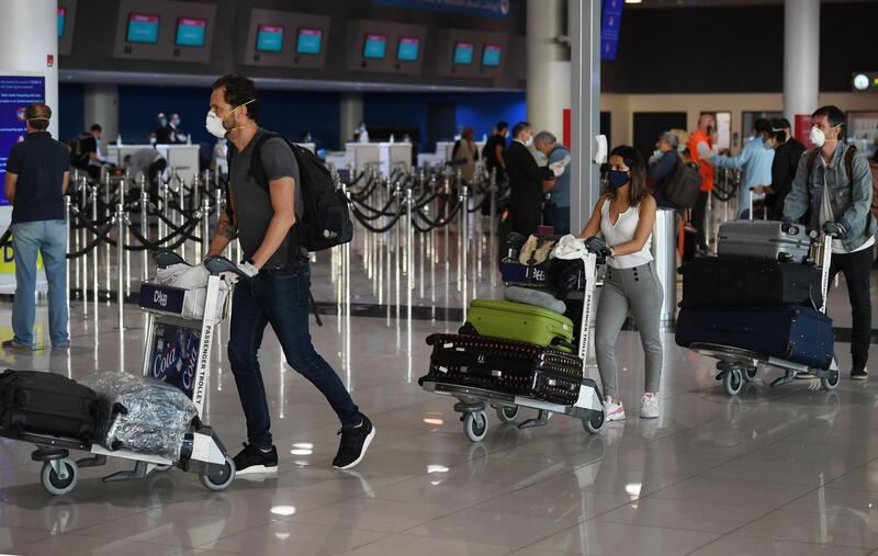 Mask-clad passengers bound for Frankfurt walk past check-in counters at Dubai International Airport.