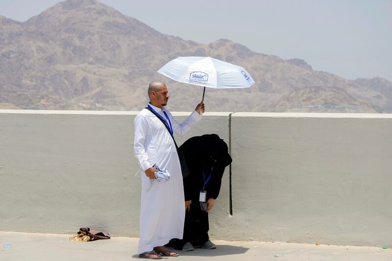 A pilgrim holds an umbrella as his wife prays, before they cast stones at a pillar in the symbolic stoning of the devil, in Mina, south-east of the holy city of Makkah, during the Hajj. AP