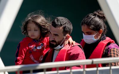 A young girl is carried by a group of people thought to be migrants as they are brought in to Dover, UK. PA