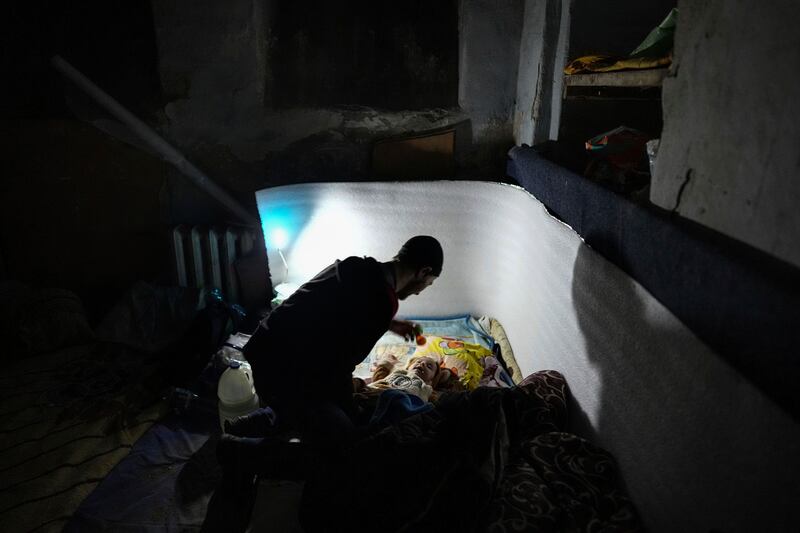 A man plays with a baby in a bomb shelter in Mariupol. AP Photo