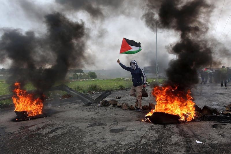 epaselect epa06637253 A Palestinian protester waves Palestine flag during clashes marking Land Day in the West Bank City of Ramallah, 30 March 2018. According to reports, seven Palestinians were killed and more than 500 injured during the clashes along the Gaza border with Israel. Clashes erupted in various locations in the West Bank and alongside the Israeli borders with Gaza as Palestinians hold protests on the occasion of Land Day, the annual day commemorating the events of 30 March 1976 when marches and a general strike was organized in the Arab towns in the occupied lands. The 1976 marches were against the Israeli government announcement to expropriate thousands of acres of land for settlement. It is considered a day for the right of Palestinians to return to their land.  EPA/ALAA BADARNEH