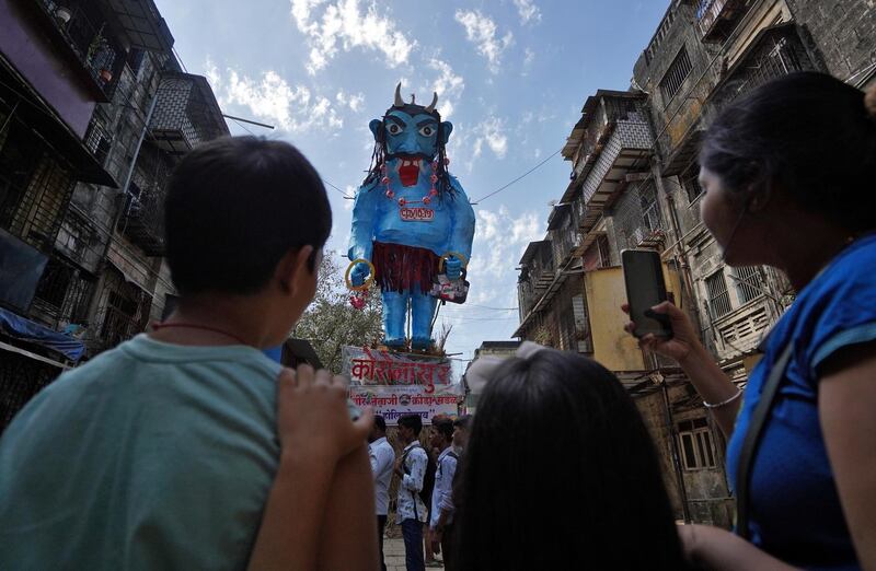 Children take photographs of an effigy depicting the coronavirus, that was burned during a ritual known as "Holika Dahan", which is part of Holi festival celebrations, at a residential area in Mumbai, India, March 9, 2020. Reuters