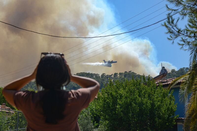 A firefighting aircraft drops water to extinguish a massive bushfire near Marmaris, Turkey.