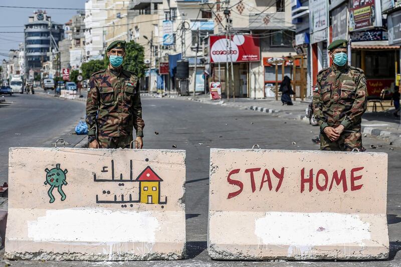 Mask-clad policemen loyal to Hamas stand behind concrete barriers painted with messages instructing people to remain at home at a checkpoint in Rafah in the southern Gaza Strip. AFP