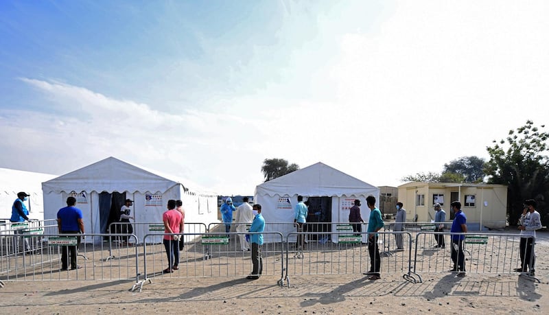 Workers stand in line to be tested for coronavirus at a clinic in Al Quoz, Dubai. Karim Sahib / AFP