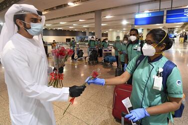 An Emirati official presents a rose to an Indian health worker, part of an 80 person medical team, upon their arrival at Dubai International Airport on May 9, 2020. / AFP / Karim SAHIB