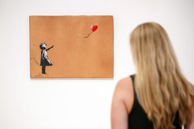 A gallery assistant poses with 'Girl with Balloon' 2006 artwork by Banksy at Lazinc Gallery in London on July 11, 2018.
The exhibition opens to the public on July 12, 2018. / AFP PHOTO / Tolga AKMEN / RESTRICTED TO EDITORIAL USE - MANDATORY MENTION OF THE ARTIST UPON PUBLICATION - TO ILLUSTRATE THE EVENT AS SPECIFIED IN THE CAPTION