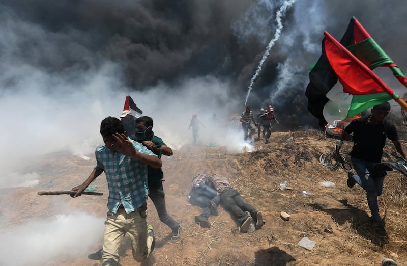Palestinian demonstrators run for cover. Ibraheem Abu Mustafa / Reuters
