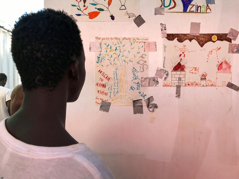 A rescued migrant called Dame Diop looks at the baobab he drew.