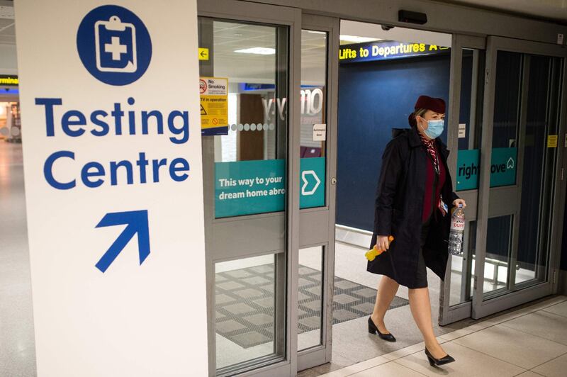 A member of flight crew walks past a sign directing people to a Covid-19 testing site adjacent to Terminal 1 of Manchester Airport. AFP