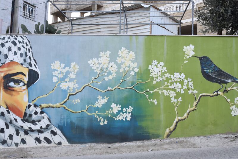 A mural of a person in a keffiyeh and a Palestine songbird, in the West Bank village of Beitin. 