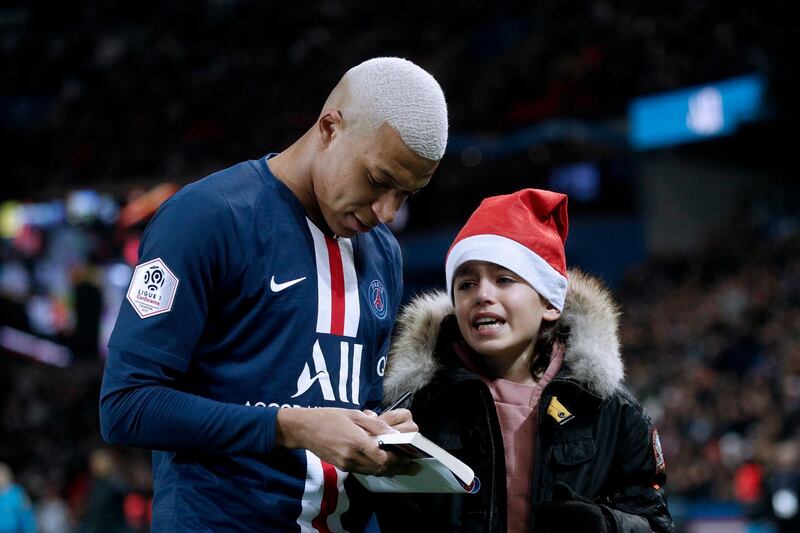 Kylian Mbappe chats with a young pitch invader. EPA