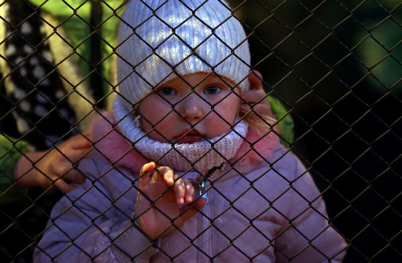 Ukrainian refugee Karolina, aged 3, from Nikopol, looks through a fence as she arrives at Przemysl Glowny train station. Reuters
