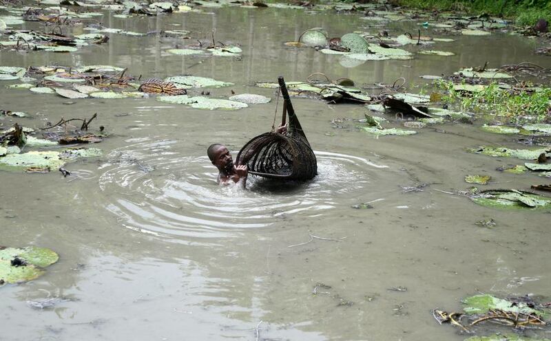 A farmer carries a basket with his catch of water snails in a pond in the village of Surjapur.  Diptendu Dutta / AFP