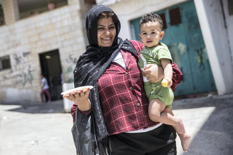 Palestinian woman Amman Rajara ,20, carries a plate of humous and a child in the Aida refugee camp near the city of Bethlehem on June 23,2019.Photo by Heidi Levine for The National