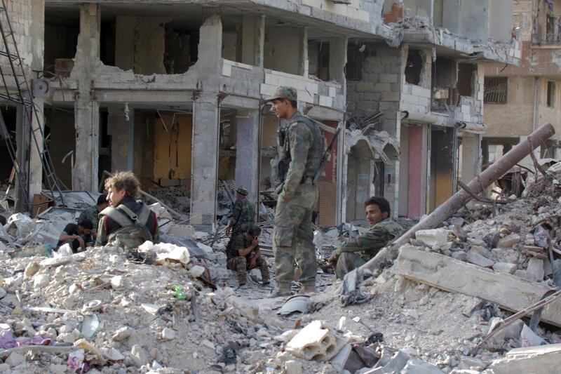 epa06754751 Syrian soldiers sit in the rubble al-Hajar al-Aswad neighborhood in south Damascus, Syria, 21 May 2018. According to reports, the Syrian army claims it has regained full control over Damascus' surrounding areas. State TV reports that the army cleared the area and the adjacent al-Yarmouk camp after killing large number of ISIS fighters.  EPA/YOUSSEF BADAWI