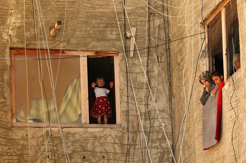 Syrian refugees watch from their window as others get tested for Covid-19 in the southern city of Sidon. AFP