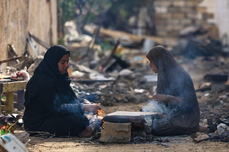 Palestinian women bake on wood fire outside their damaged homes in Khezaa district, near Khan Younis. AFP