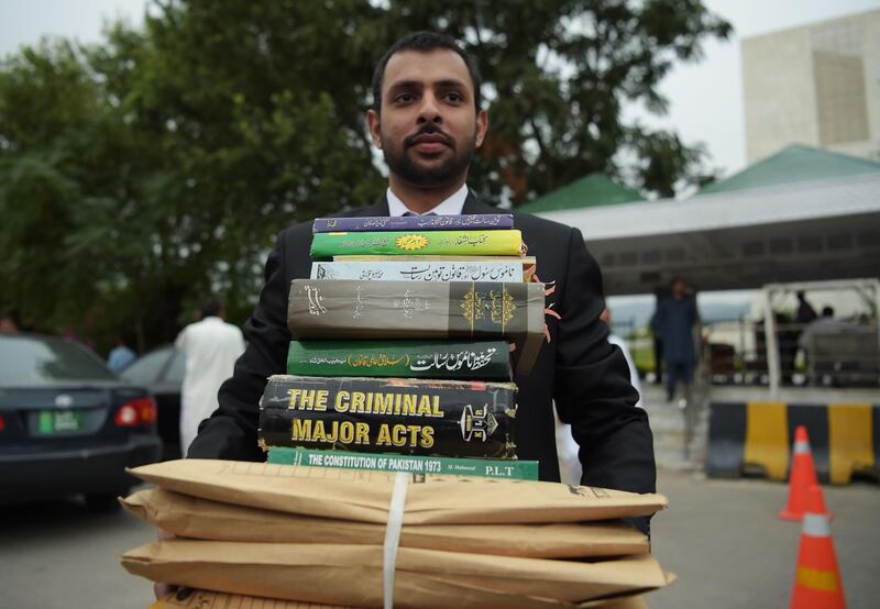 A team member of Chaudhry Ghulam Mustafa (unseen), a Pakistani lawyer representing a petitioner against a Christian mother Asia Bibi, carries legal books as they leave with his team the Supreme Court after the final hearing in Islamabad on October 8, 2018. Pakistan's Supreme Court said it had reached a judgement on October 8 after hearing the final appeal of a Christian mother on death row for blasphemy, but that it will announce its ruling later in the notorious case, which has gone all the way to the Vatican. / AFP / AAMIR QURESHI

