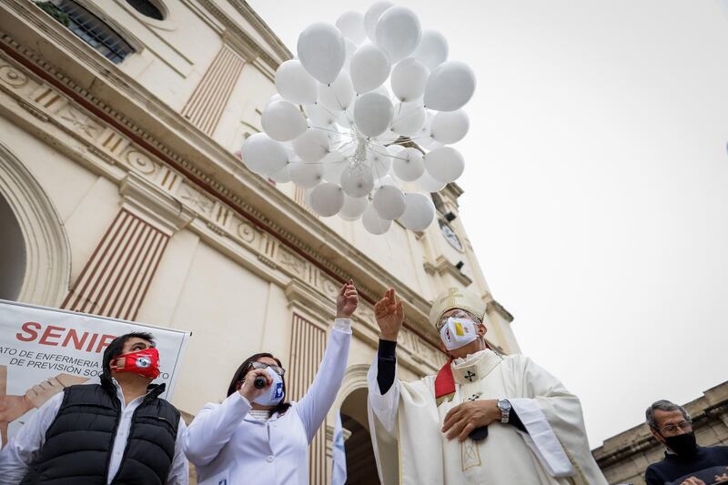 The President of the Paraguayan Nursing Association Mirna Gallardo, centre left, and Edmundo Valenzuela, right, archbishop of Asuncion, launch 60 balloons in commemoration of the 60 nurses and doctors who died due to Covid-19, in the Metropolitan Cathedral of Asuncion, Paraguay. EPA