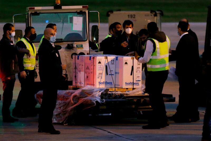 Workers stand next to boxes of the Pfizer-BioNTech vaccine at Rafik Hariri International Airport in Beirut on February 13, 2021. AP Photo