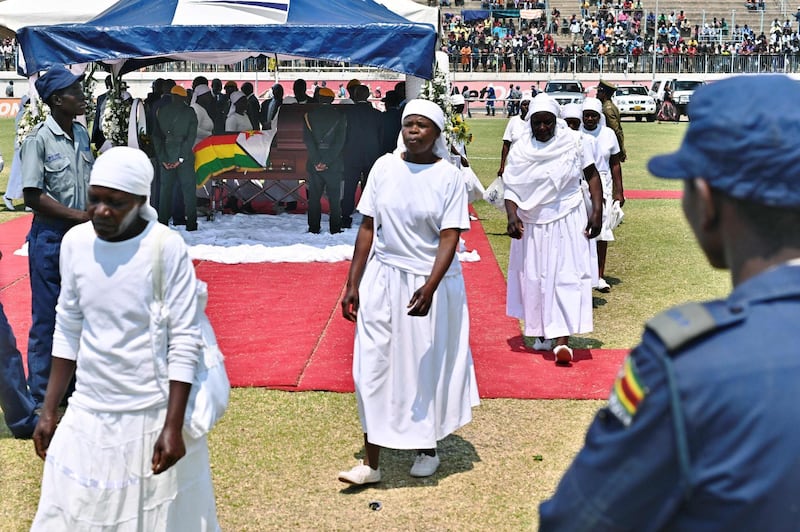 Members of public walks past the casket of Zimbabwe's former President, the late Robert Mugabe during a public viewing at Rufaro stadium where his body lays in state for a second day. Mugabe died in Singapore last week aged 95, leaving Zimbabweans divided over the legacy of a leader once lauded as a colonial-era liberation hero, but whose autocratic 37-year rule ended in a coup in 2017.  AFP