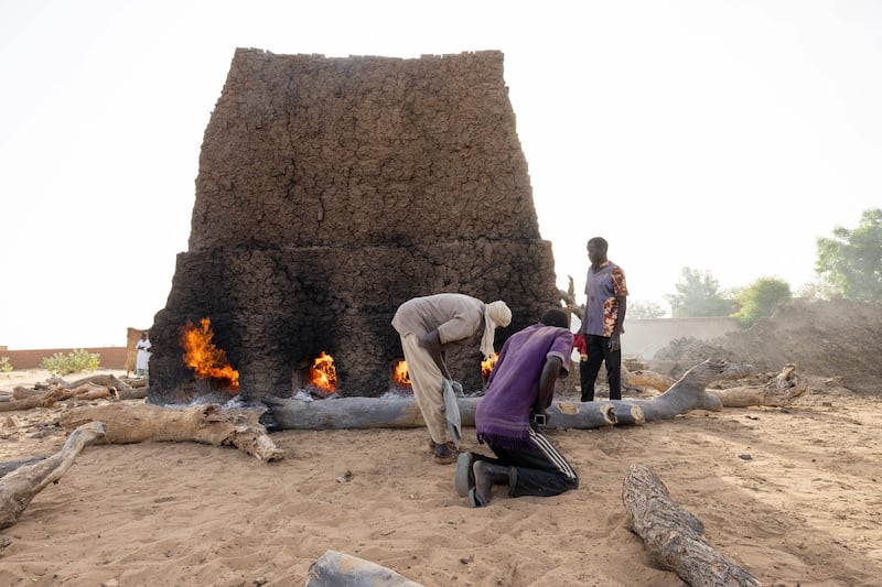 Refugees push logs into a brick oven in Adre