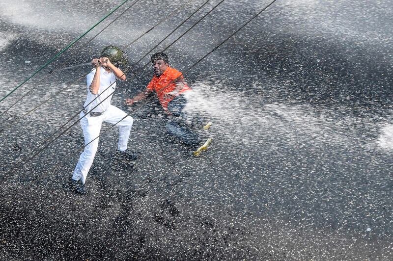 A police officer charges a BJP protester with a baton as police fire water cannon during a protest rally against the Trinamool Congress (TMC) led-state government in Kolkata. AFP