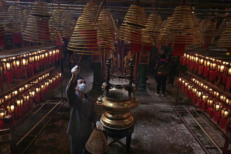 A worker wearing a mask adjusts joss sticks at the Man Mo Miu Temple on the third day of the Lunar New Year in Hong Kong. Vincent Yu / AP Photo