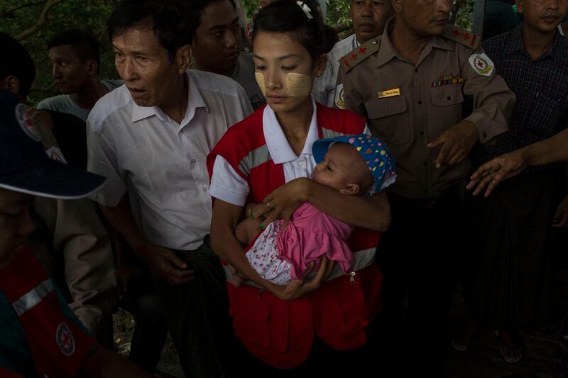 TOPSHOT - A member of Myanmar's Red Cross carries a baby as he arrives in Sittwe jetty, in Rakhine State on August 30, 2017.
At least 18,500 Rohingya have fled into Bangladesh in the last six days since renewed fighting broke out between militants and the army in neighbouring Myanmar, the International Organization for Migration said. / AFP PHOTO / STRINGER