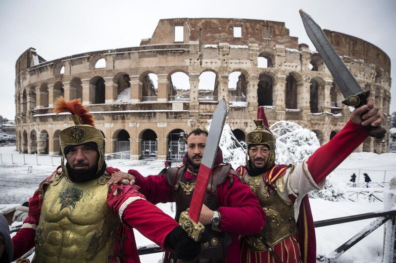 epa06566424 Men posing as a centurions in front of the Colosseum covered by snow during a snowfall in Rome, Italy, 26 February 2018. Media reports on 26 February state that extreme cold weather is forecast to hit many parts of Europe with temperatures plummeting to a possible ten year low.  EPA/ANGELO CARCONI