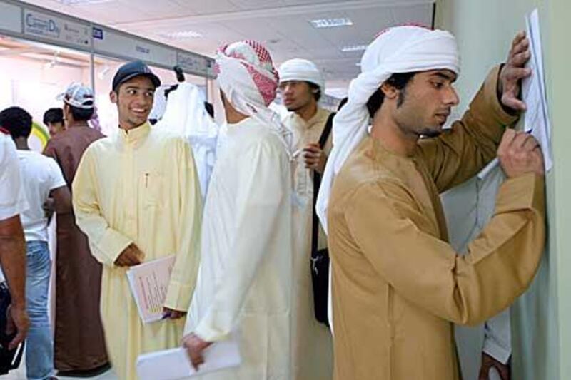 Emirati students looking for a job in the private sector fill up forms during a career fair held at Men's Dubai College.