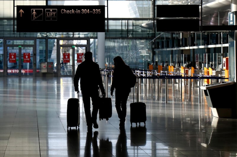 FILE - In this Saturday, Dec. 26, 2020 file photo, people walk with their luggage through a deserted check-in hall at the airport in Munich, Germany as Germany continues its second lockdown to avoid the further outspread of the coronavirus. On Tuesday, Jan. 12, 2021, the U.S. government said it will require airline passengers entering the country to show proof of a negative COVID-19 test before boarding their flights. It will take effect Jan. 26. (AP Photo/Matthias Schrader)