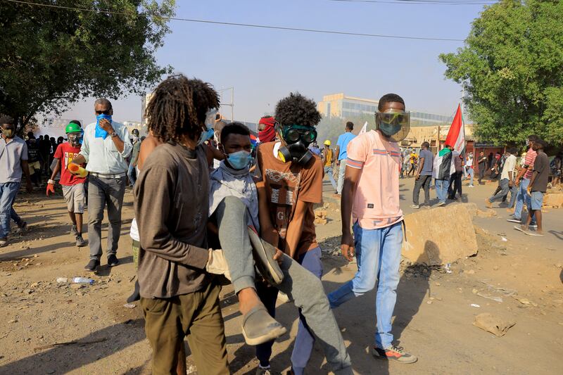 Sudanese anti-military protesters carry an injured demonstrator in Khartoum. Photo: Reuters.