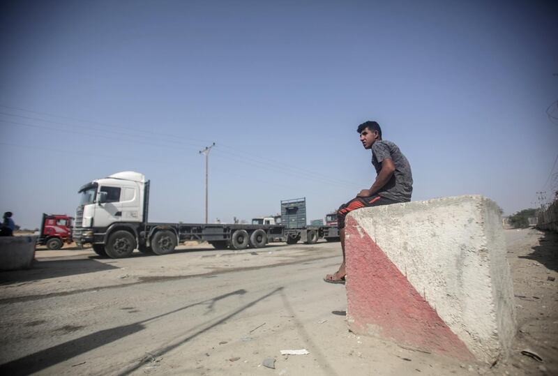 epa07109437 A Palestinian child looks at trucks at the gate of the Kerem Shalom crossing, the main passage point for goods entering Gaza, in Rafah town in the southern Gaza Strip, 21 October 2018. According to media reports, Israeli authorities announced that the Kerem Shalom crossing in the southern Gaza Strip and the Erez crossing (Beit Hanoun) in northern Gaza will be reopened on 21 October.  EPA/HAITHAM IMAD