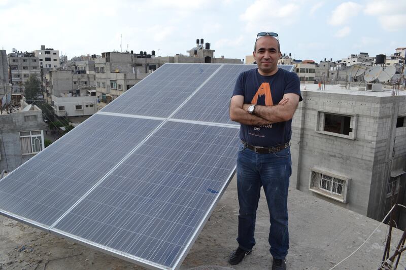 Muhammad Dahman stands near the solar energy panels he installed on his roof in Gaza City. Naomi Zeveloff for The National